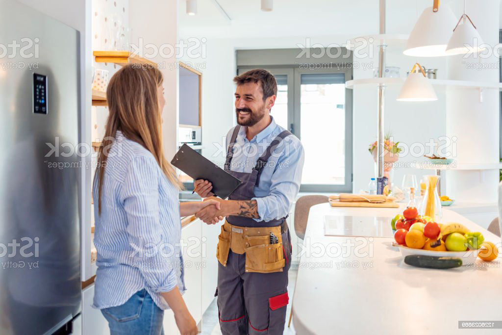 Young Woman Shaking Hands To Male Plumber With Clipboard In Kitchen Room